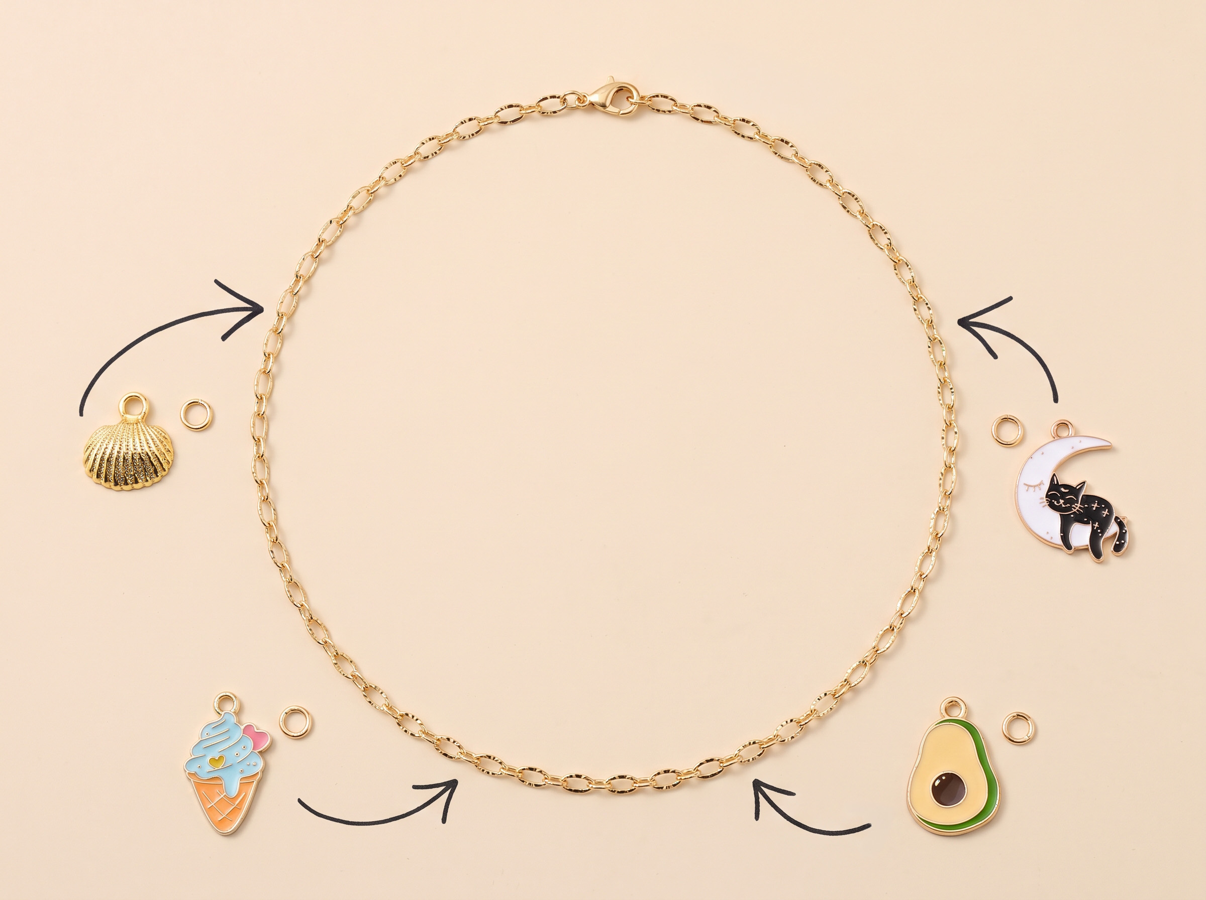 Chaîne dorée entourée de charms coquillage, chat sur la lune, glace et avocat, avec des flèches qui montrent où les accrocher