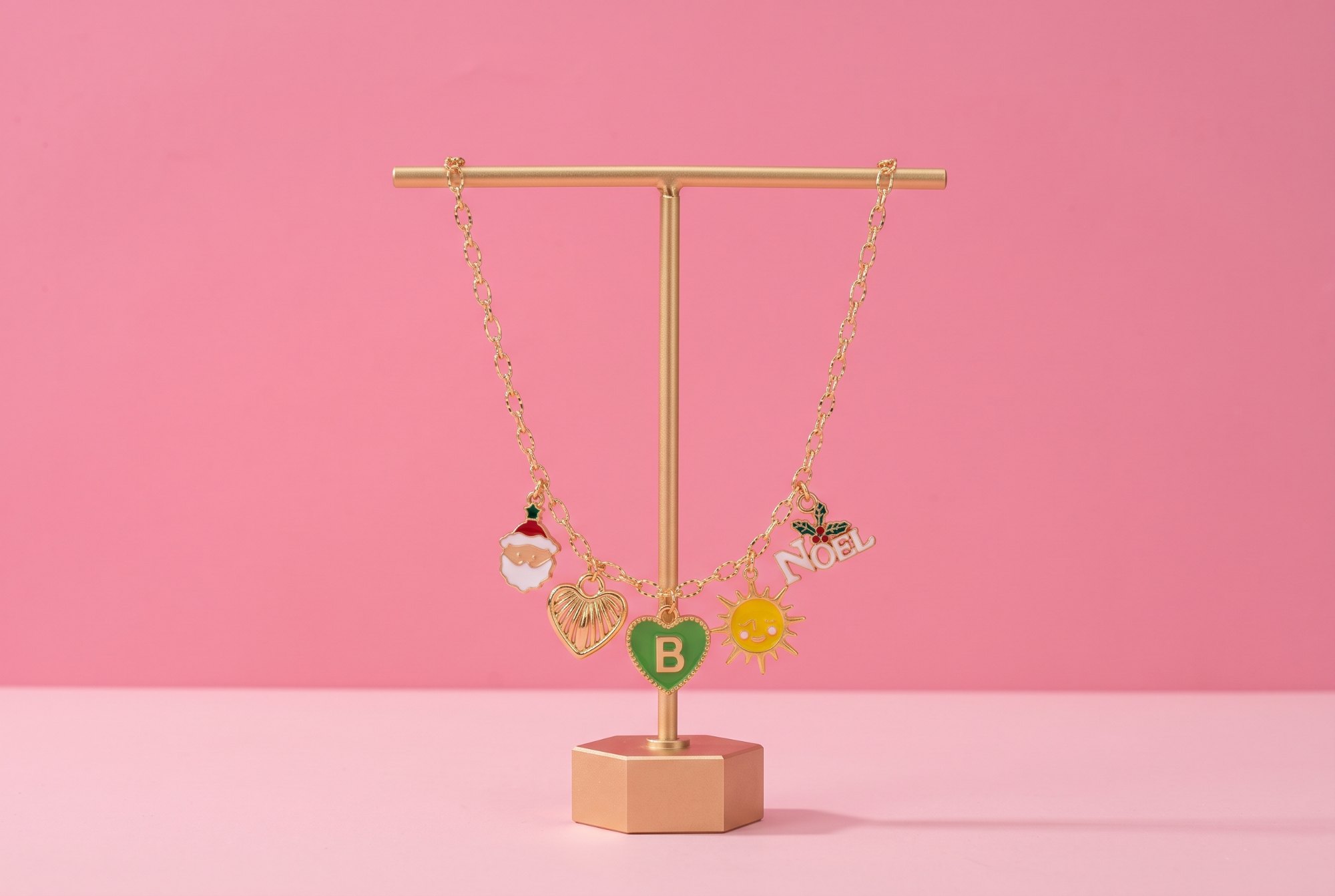 Collier de Noël Bibeejoy sur un présentoir doré : Père Noël, cœur doré, initiale B, soleil et NOËL
